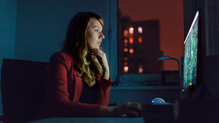 A woman sitting in front of a computer at night.