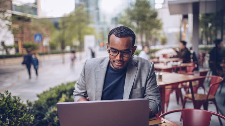 A businessman using a laptop at an outdoor cafe.