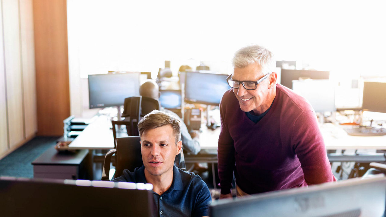 Two men in an office looking at a computer screen.