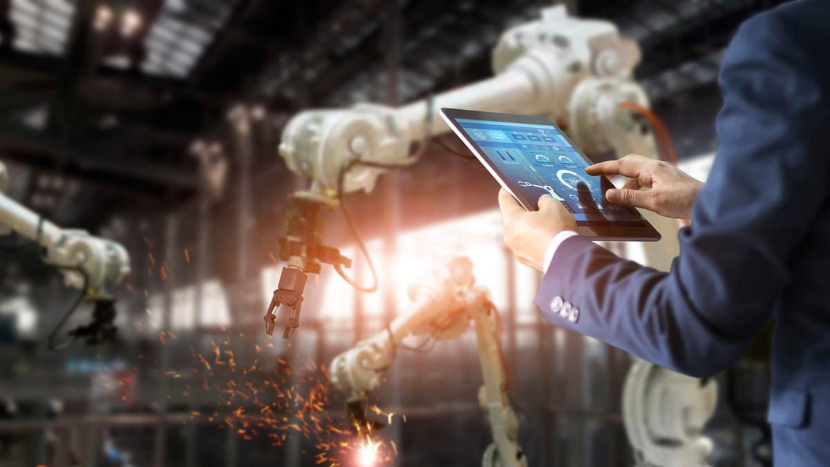 A man in a suit is using a tablet in front of robots.