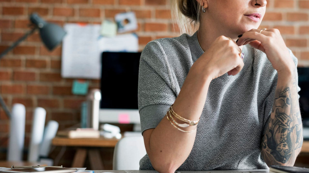 A woman sitting at a desk looking at her phone.
