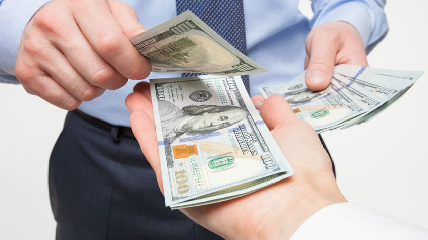 A businessman is handing out money to another person.