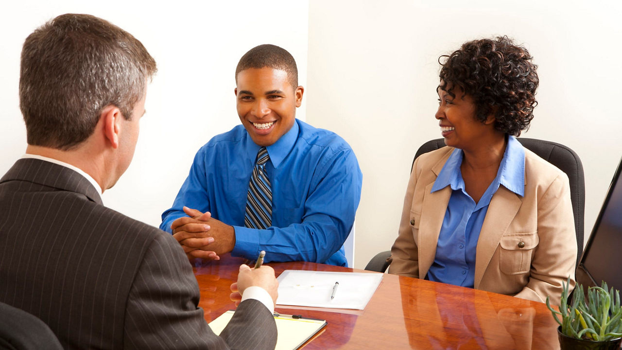 A group of people sitting at a desk in an office.
