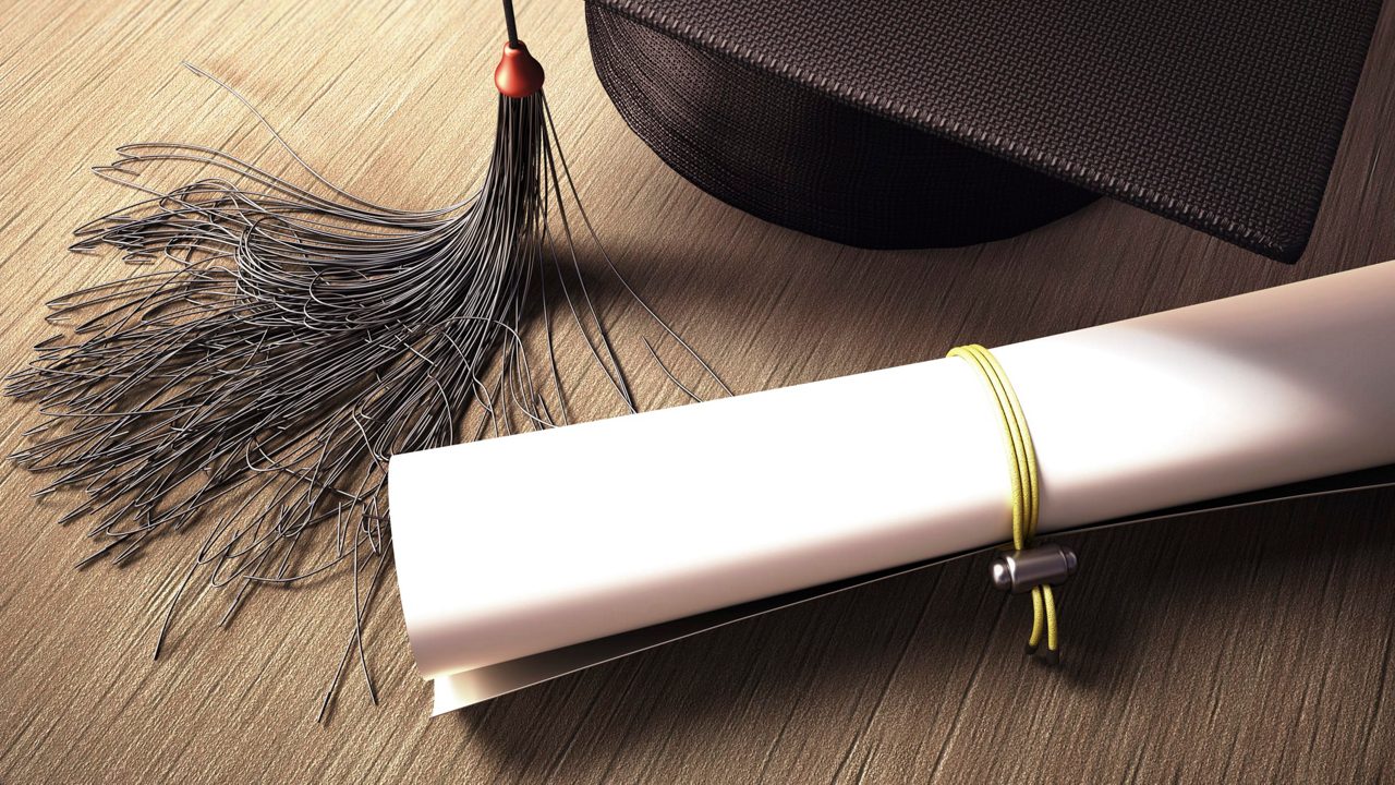 A graduation cap and diploma on a wooden table.