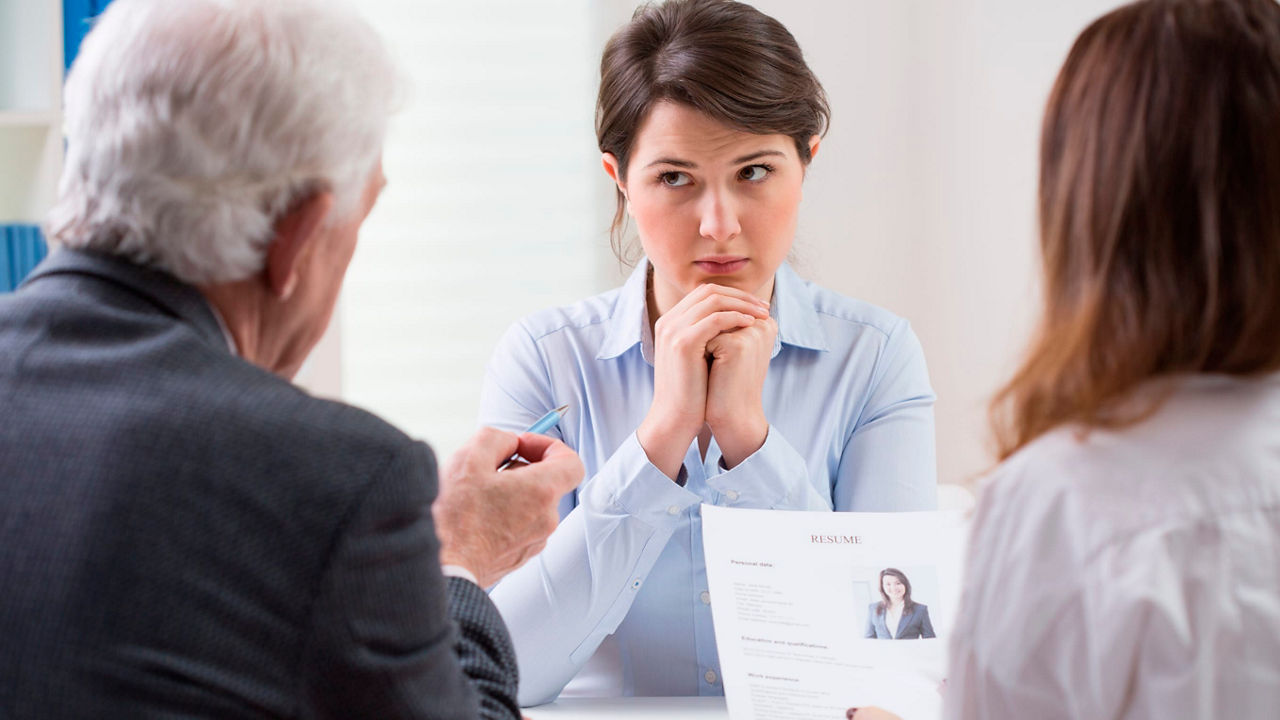 A woman is sitting at a table with a man looking at her resume.