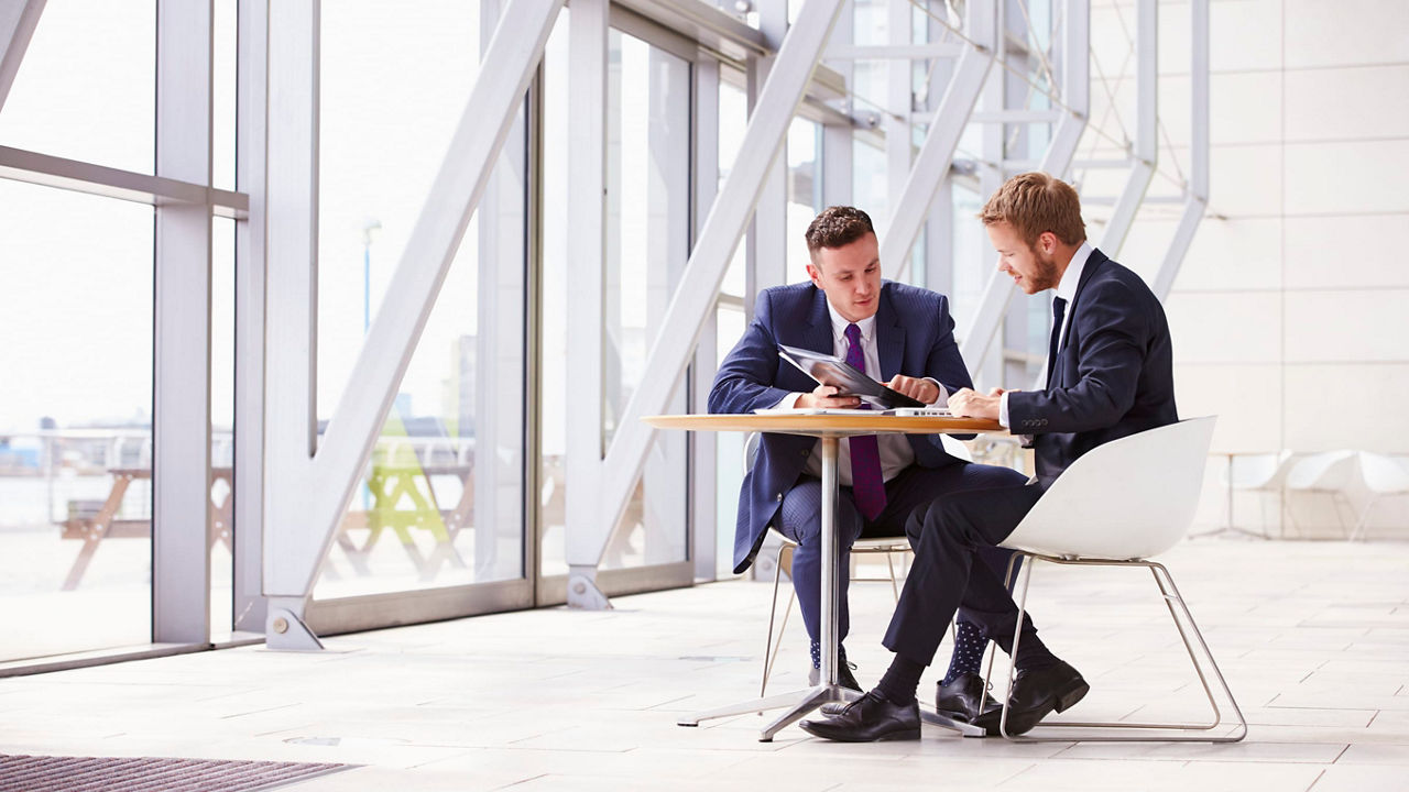 Two businessmen sitting at a table in an office.