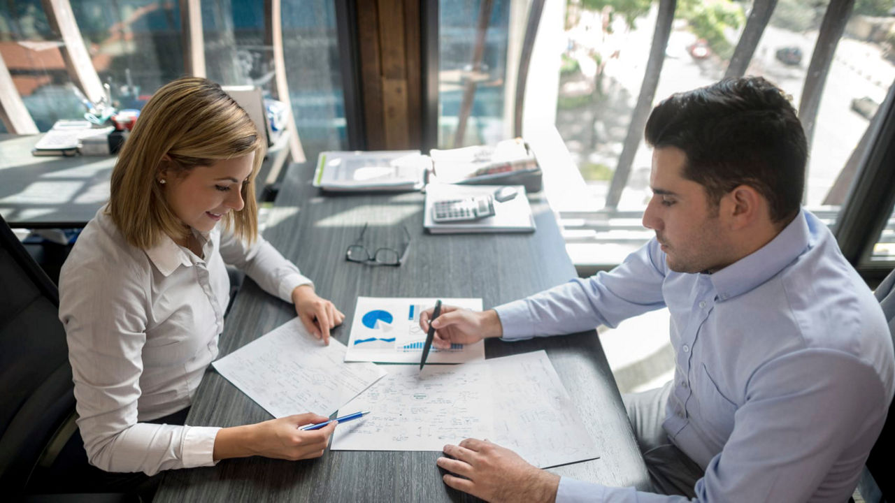 A man and woman sitting at a desk in an office.