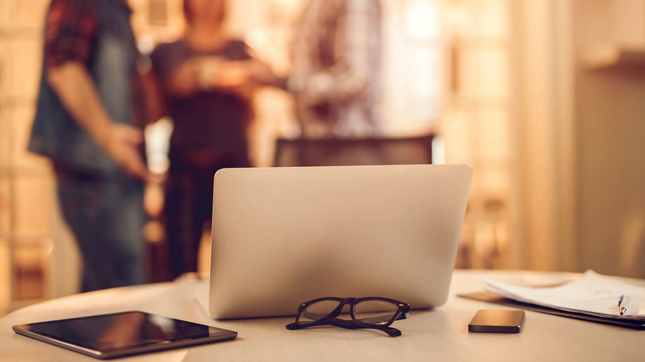 A group of people standing around a laptop on a table.