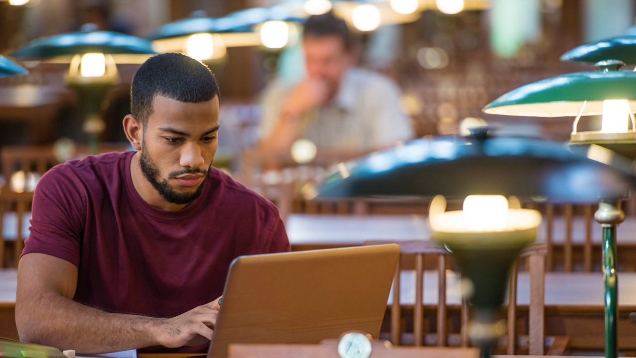 A man working on a laptop in a library.