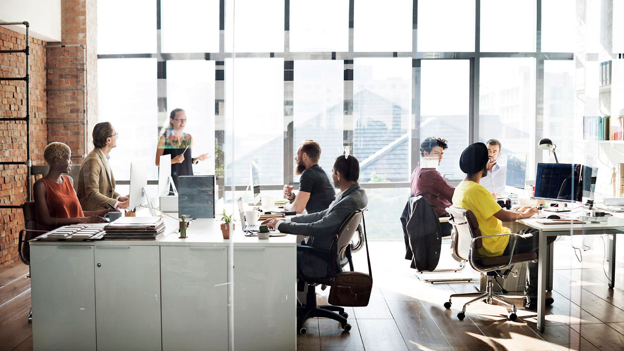 A group of people sitting at desks in an office.