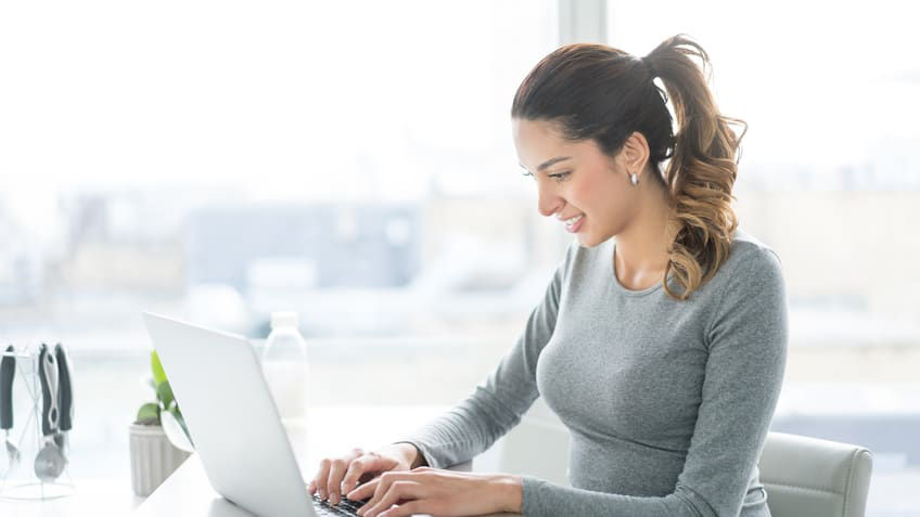 A woman working on a laptop in an office.