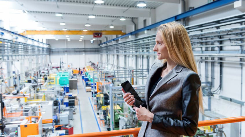 A woman in a factory looking at a tablet computer.