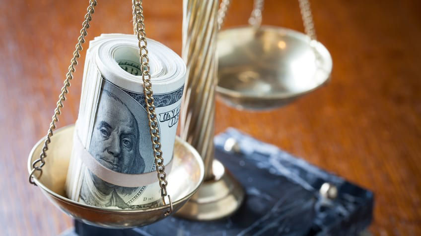 A balance scale with a dollar bill on it.