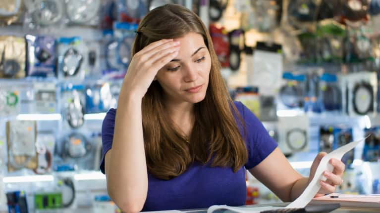 A woman is looking at a paper in a store.