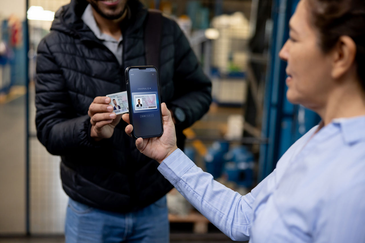 Supervisor scanning the ID of a warehouse worker at the door - people arriving to work concepts
