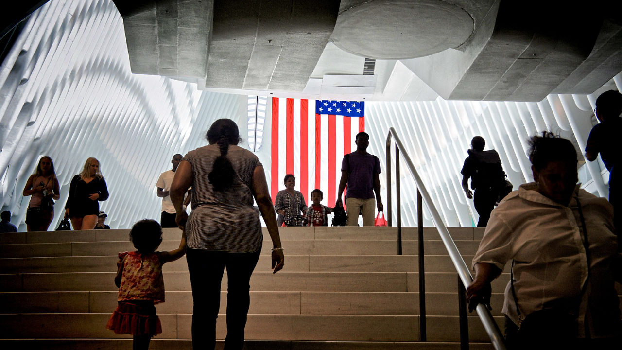 A group of people walking down stairs with an american flag in the background.
