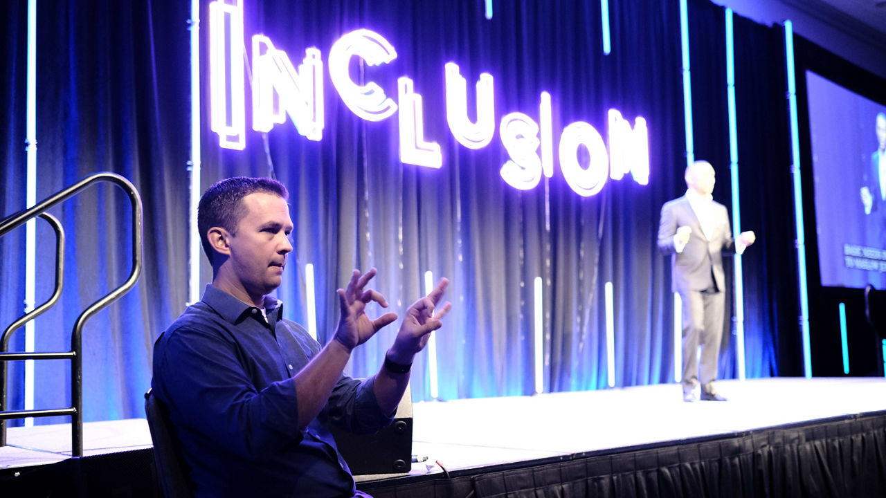 A man is speaking on stage at an event.