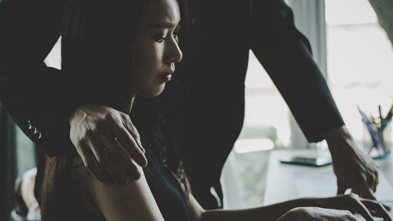 A man is helping a woman on a laptop.