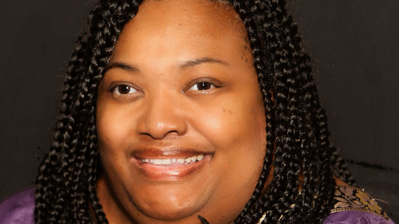 A woman with braided hair smiling for the camera.