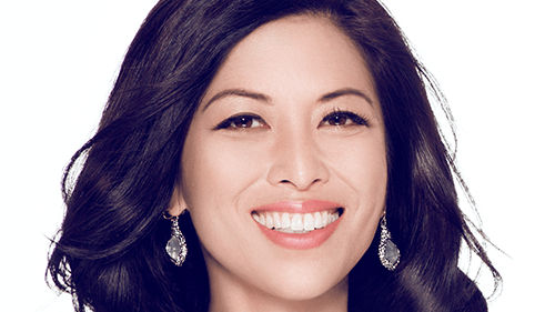 A smiling woman in a black and white dress.