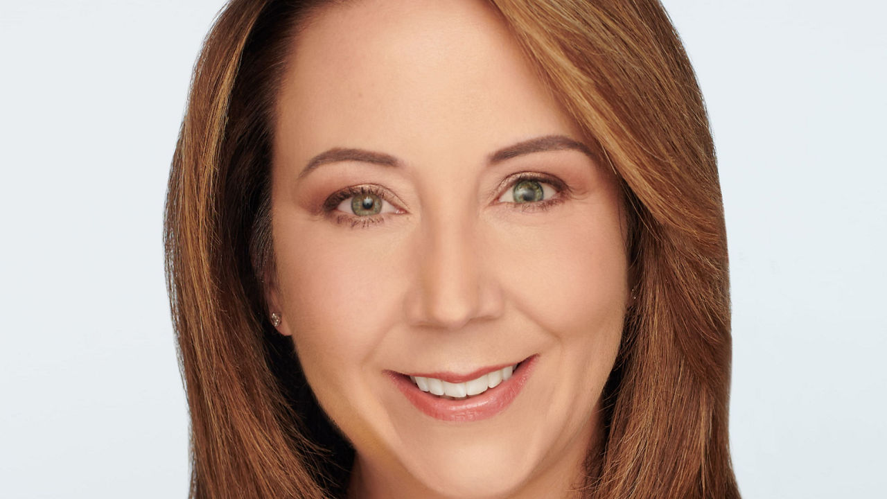 A woman in a red shirt smiling.