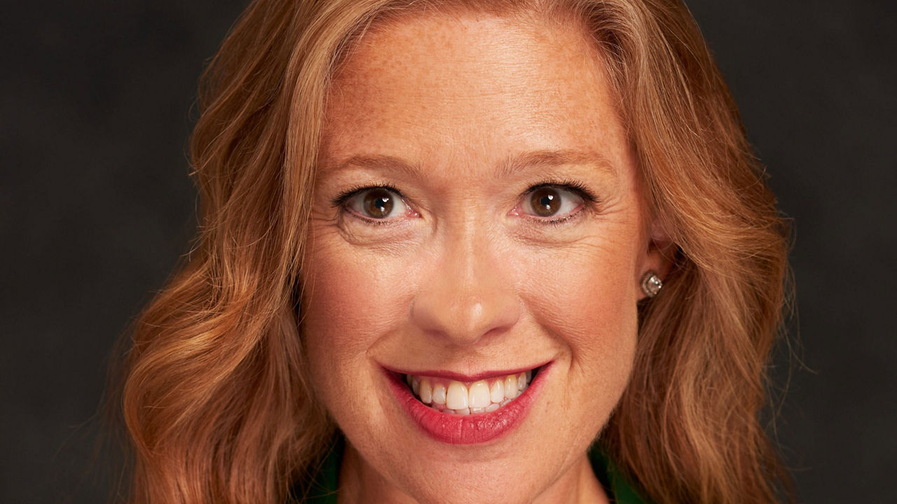 A woman in a green blazer smiling.