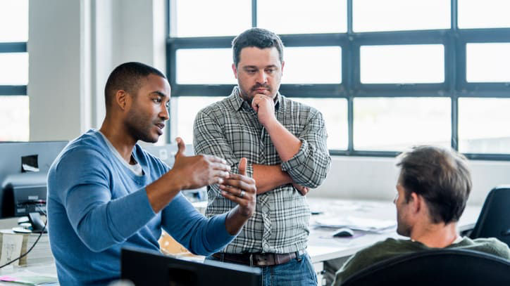 A group of people in an office talking to each other.