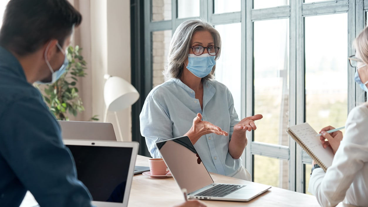 A group of people wearing face masks in an office.