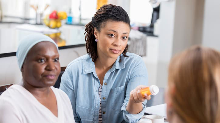 Two women talking to a doctor at a kitchen table.
