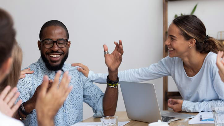 Coworkers patting man on back