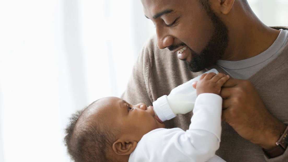 A man feeding his baby with a bottle.