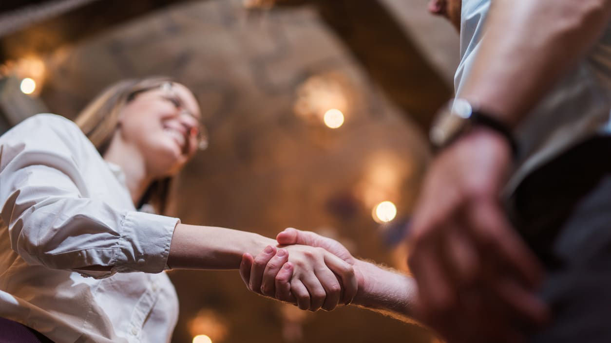 A man and woman shaking hands in a restaurant.