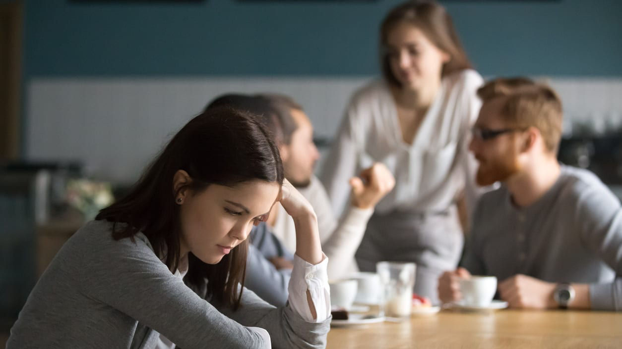 A woman is sitting at a table with a group of people around her.
