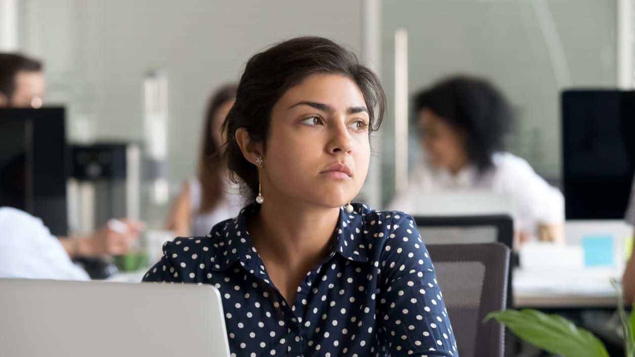 A woman sitting in an office looking at her laptop.