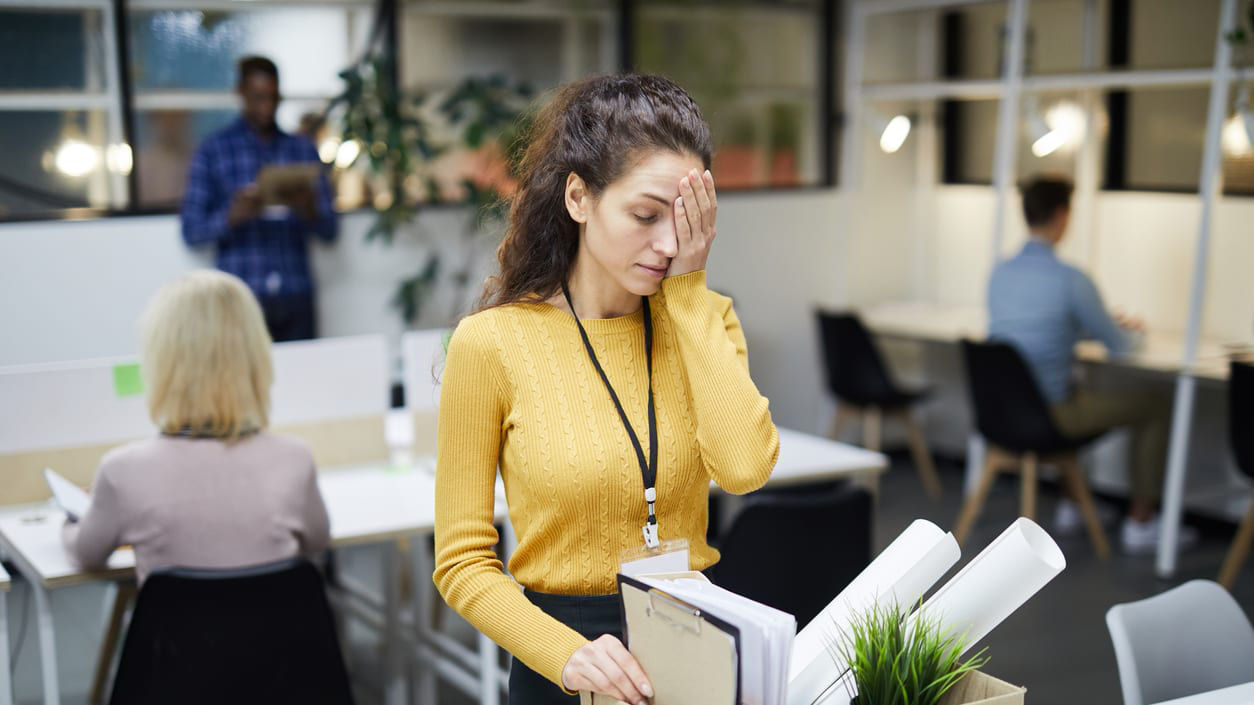 A woman is standing in an office holding a box.