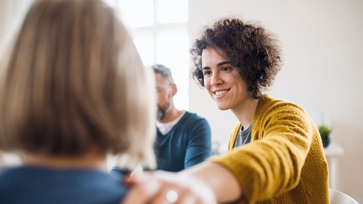 A woman is talking to another woman in a meeting.