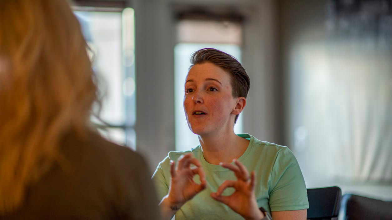 A woman sitting at a table talking to another woman.