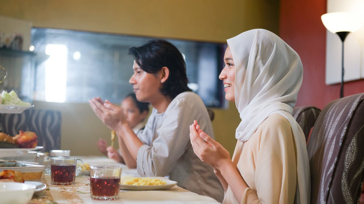 People sitting at a dinner table with tea and plates of rice.
