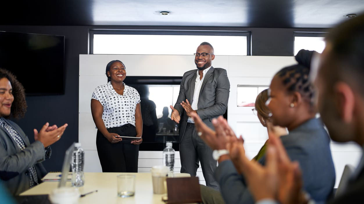 A group of business people clapping at a meeting.