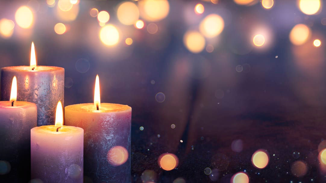 Three candles on a dark background with bokeh lights.