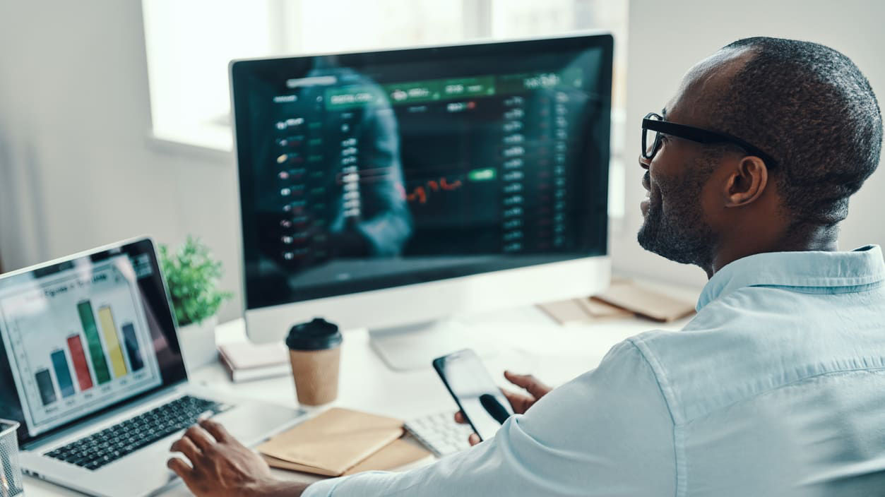 A man sitting at a desk looking at a computer screen.