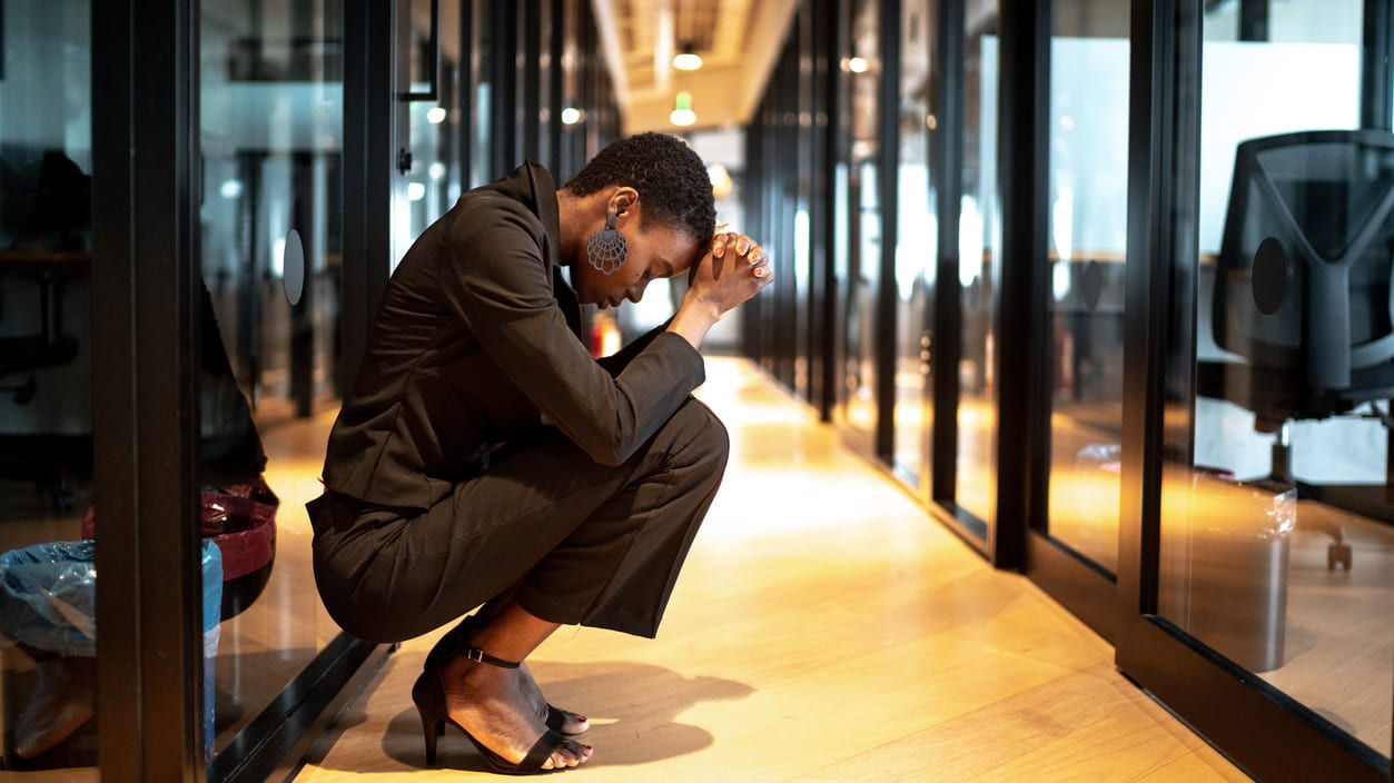 A woman in a business suit kneeling on the floor in an office.