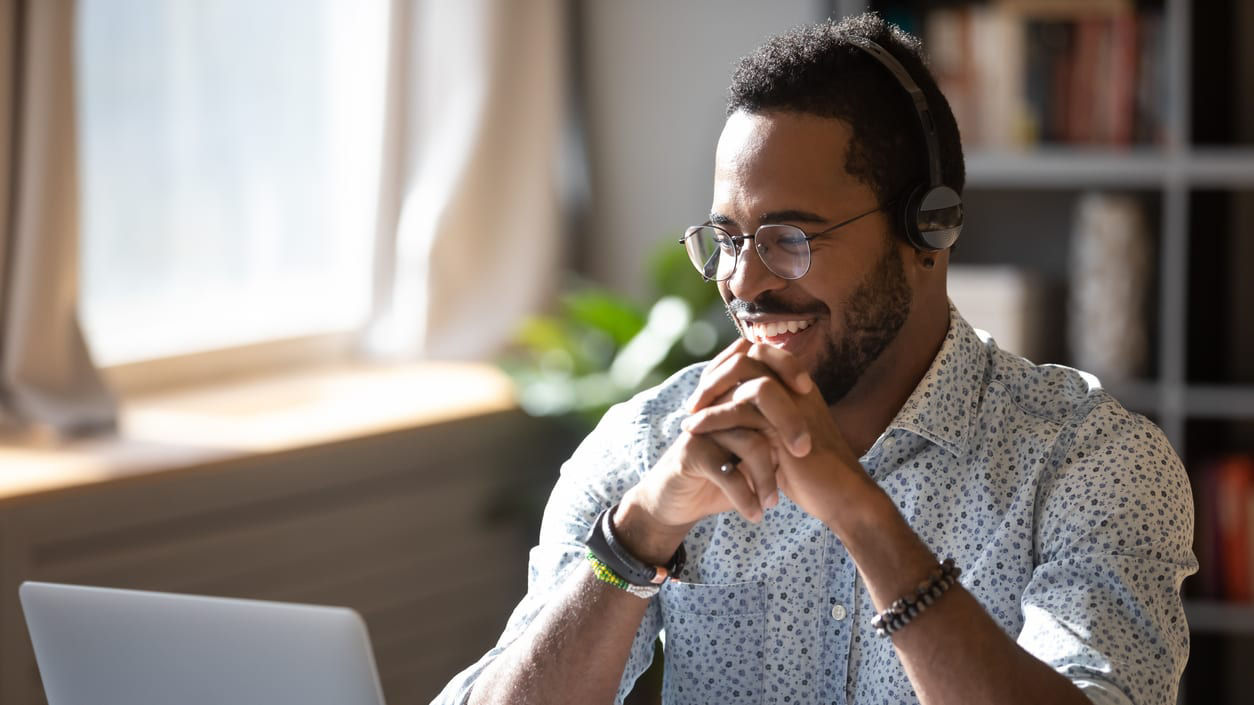 A man wearing a headset while working on a laptop.