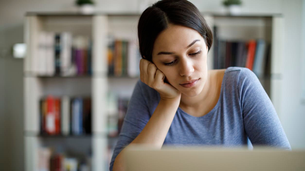 A woman is sitting at a desk with a laptop in front of her.