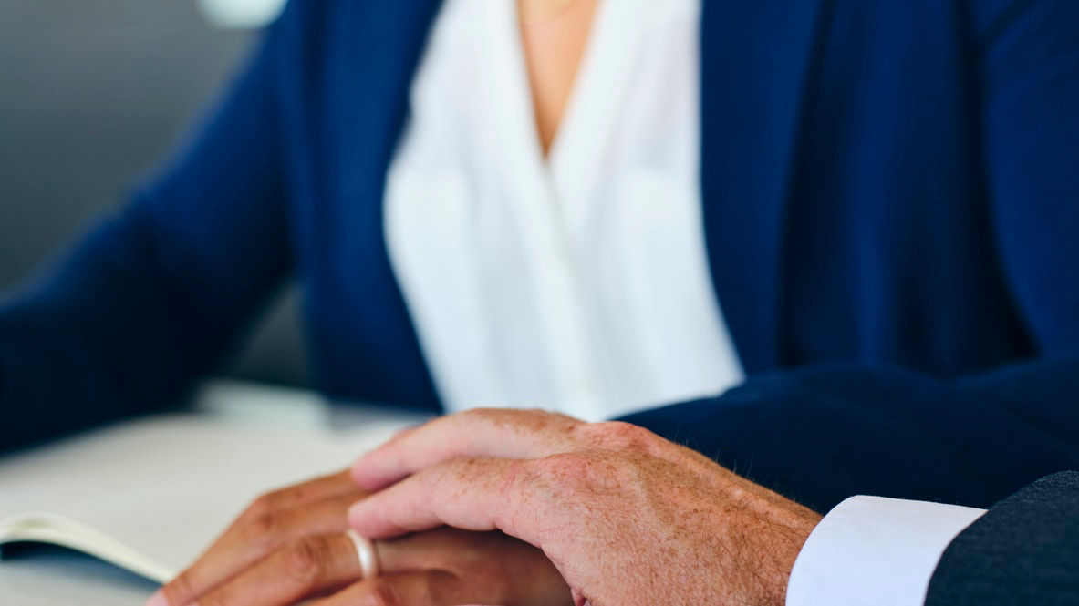 Two business people holding hands at a table.