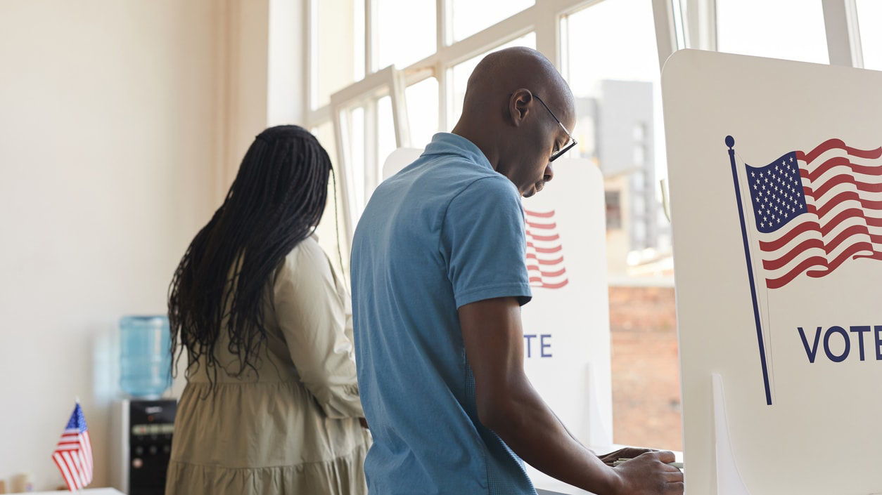 A man and woman voting in a voting booth.