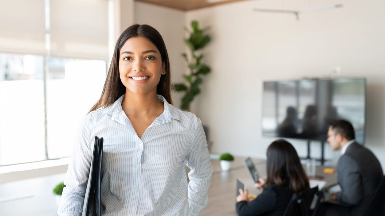 A business woman holding a folder in front of a group of people.