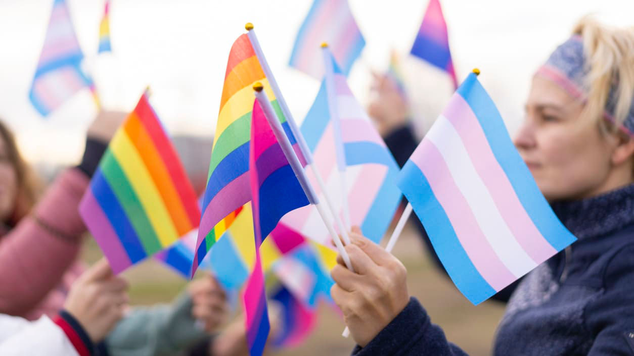 A group of people waving rainbow flags.