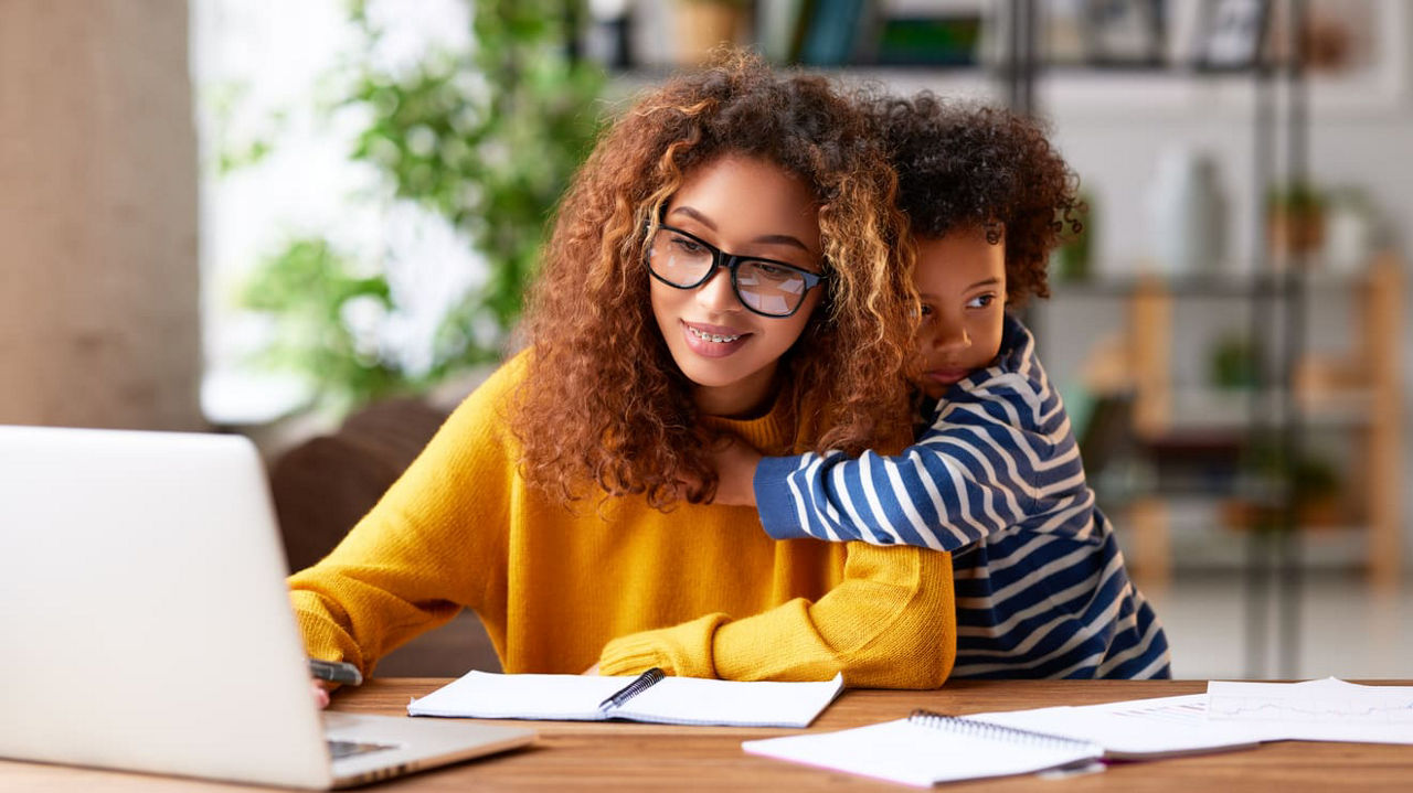 A woman and her son are working on a laptop at home.