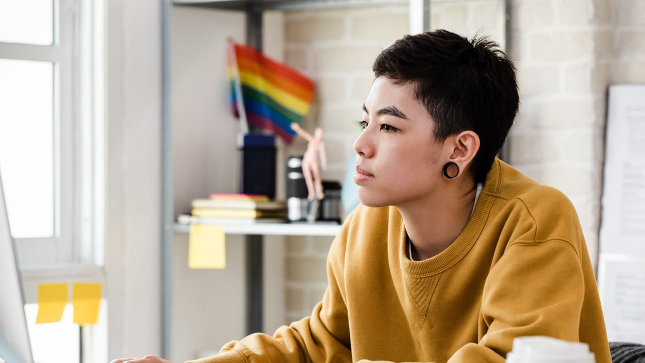 A young man sitting at a desk using a computer.